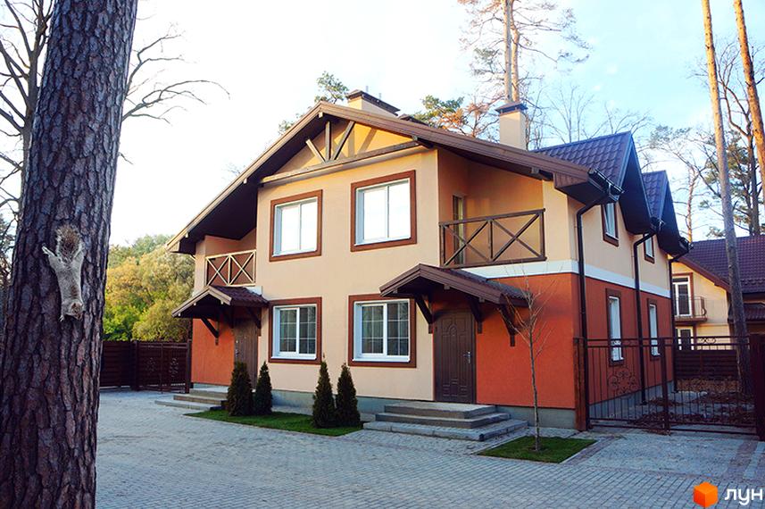 Котеджне містечко КМ Sweet Home. Двоповерхові будинки з коричневими дахами та світло-бежевими фасадами, оранжевою нижньою частиною. Прибудинкова територія з бруківкою та деревами.
