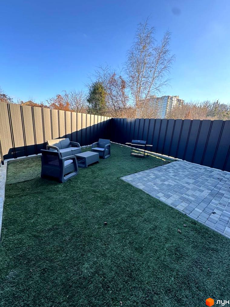 Прибудинкова територія Таунхауси 40 Estates з газоном та зоною для відпочинку. Сучасні меблі на терасі та огорожа.