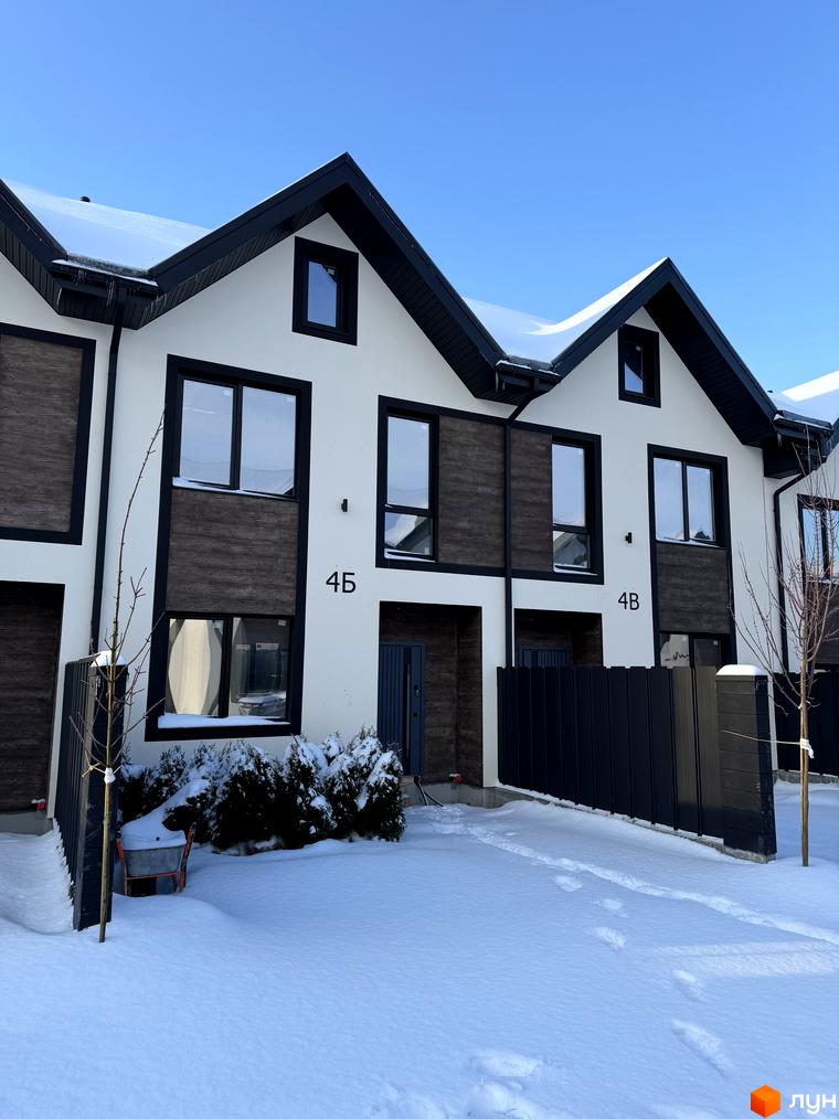 Зовнішній вигляд таунхаусів 40 Estates з білими стінами та дерев'яними елементами. Прибудинкова територія з снігом та зеленими насадженнями.