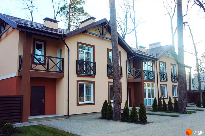 Двоповерхові будинки Котеджного містечка Sweet Home з коричневими дахами та балконами. Прибудинкова територія має зелені газони, бруківку та дерева.