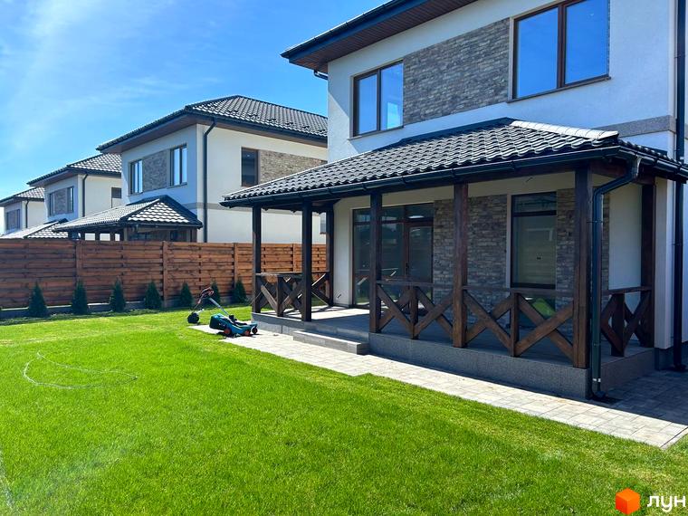 Зовнішній вигляд будинку в Комплекс Озерний з прибудинковою територією та зеленим газоном.