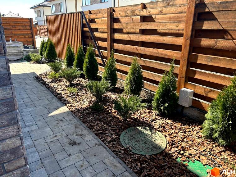 Зовнішній вигляд прибудинкової території житлового комплексу Комплекс Озерний з доріжкою та зеленими насадженнями.