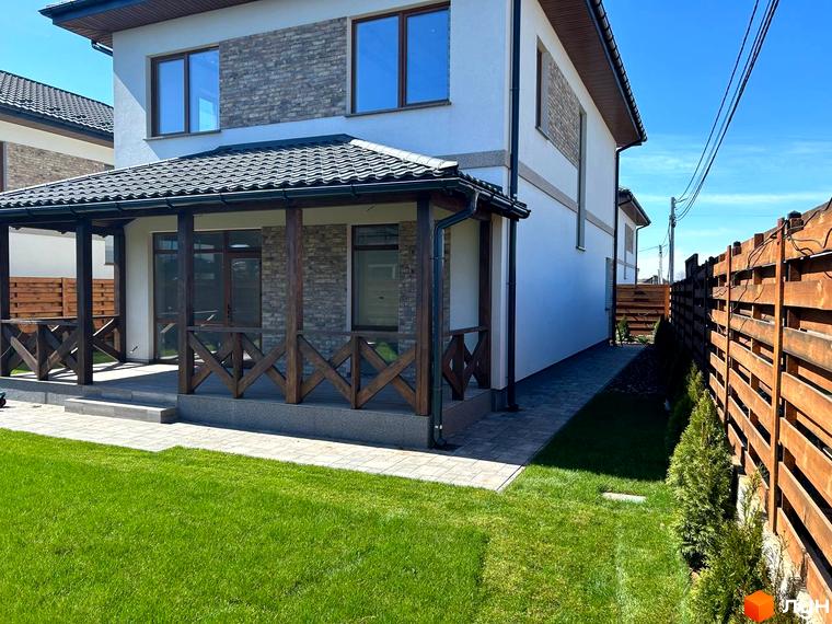 Зовнішній вигляд будинку Комплекс Озерний з верандою та прибудинковою територією, озелененою газоном і живоплотом.