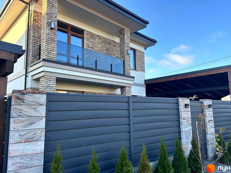 Зовнішній вигляд будинку Комплекс Незалежний з балконом та огорожею. Прибудинкова територія озеленена хвойними рослинами.