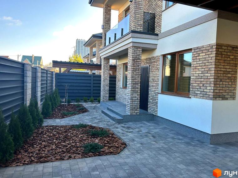 Зовнішній вигляд будинку Комплекс Незалежний з прибудинковою територією, оформленою зеленими насадженнями та мощенням.