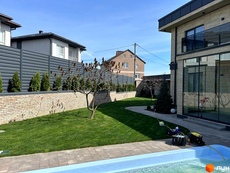 Сучасний будинок житлового комплексу Комплекс Грушевий з великими вікнами та прибудинковою територією з газоном і деревами.