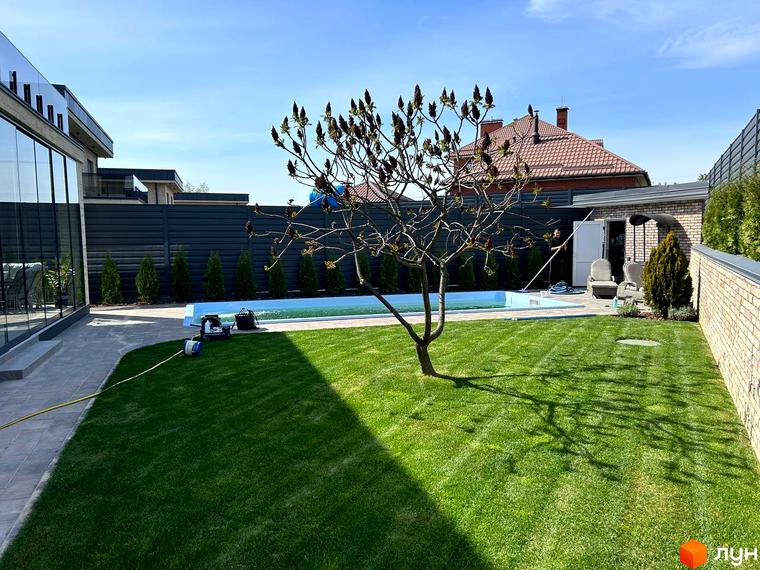 Зовнішній вигляд комплексу Грушевий з великими вікнами та прибудинковою територією з газоном і басейном.