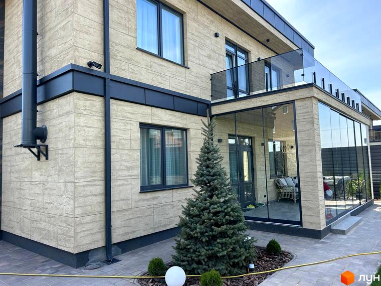 Зовнішній вигляд будинку Комплекс Грушевий з великими вікнами та балконом. Прибудинкова територія з зеленими насадженнями та тротуарною плиткою.