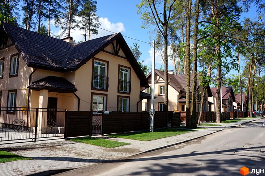 Котеджне містечко Sweet Home: двоповерхові будинки з бежевими стінами та коричневими дахами. Вулиця з тротуаром, газонами та високими деревами.