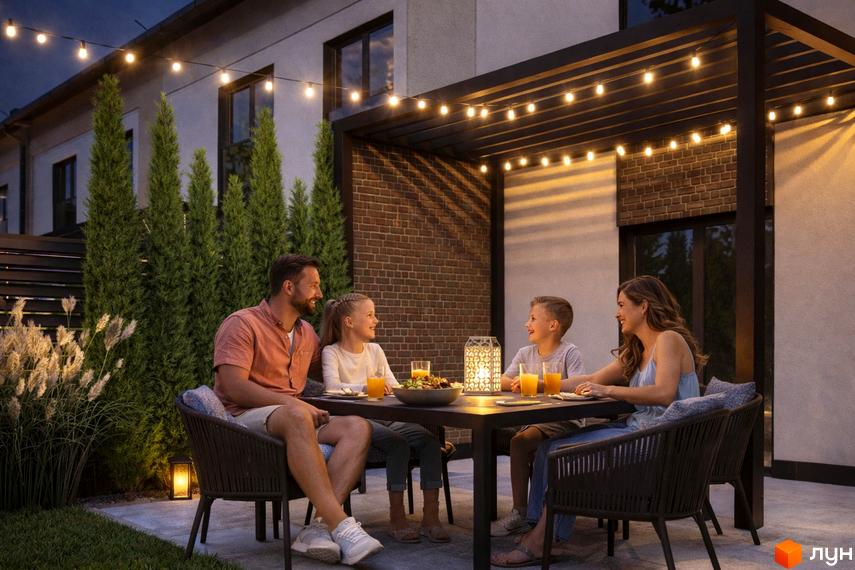 Зовнішній вигляд Таунхаусів Svoie Birky з прибудинковою територією, де сім'я проводить час за столом на терасі.