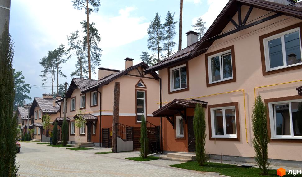 Котеджне містечко Sweet Home: ряд двоповерхових будинків з бежевими фасадами, коричневими дахами. Прибудинкова територія з бруківкою, газонами та хвойними деревами.