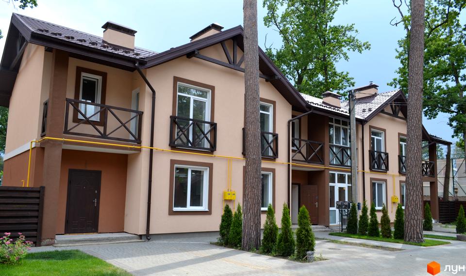 Котеджне містечко Sweet Home. Двоповерхові будинки з бежевими фасадами, коричневими дахами та балконами, вимощена доріжка та зелені насадження.