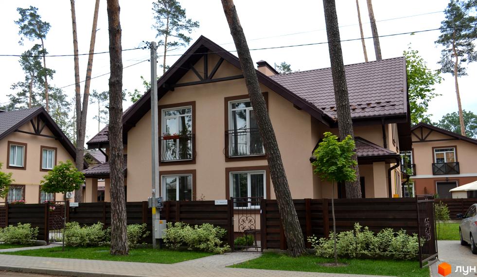 Котеджне містечко Sweet Home: бежеві будинки з коричневими дахами та білими вікнами. Територія облаштована огорожею, зеленими насадженнями та доріжками.