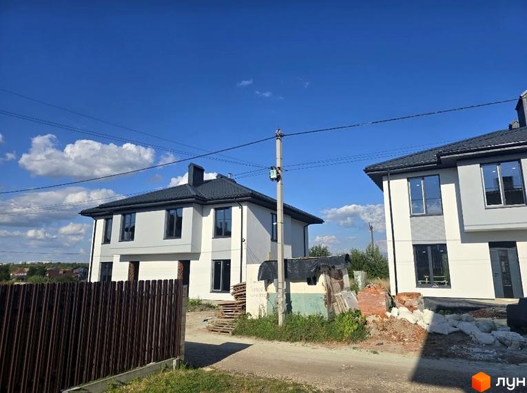 Зовнішній вигляд будинків житлового комплексу КМ Savanna з прибудинковою територією. На фоні видно чисте небо та облаштована територія.