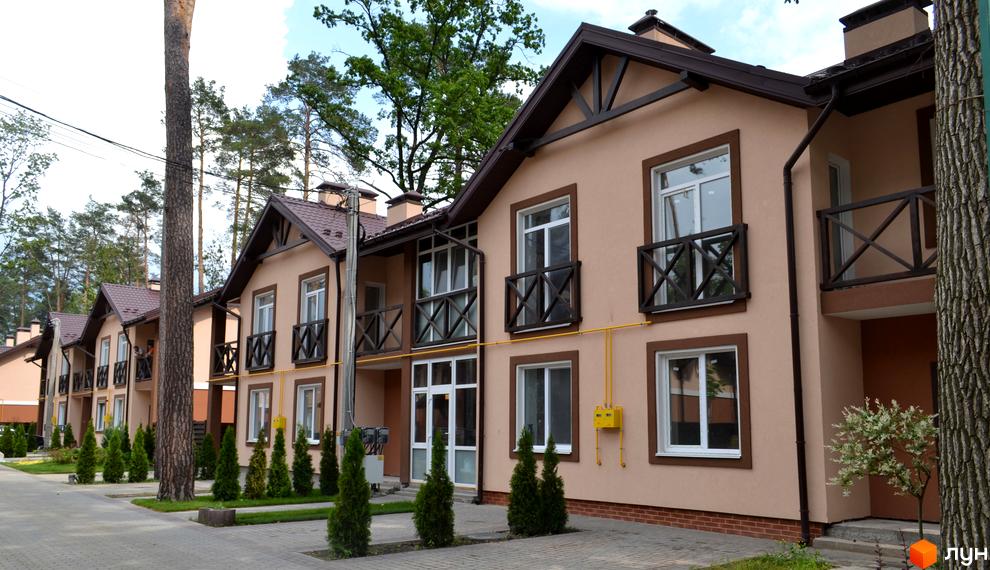 Котеджне містечко Sweet Home: ряд двоповерхових котеджів світло-коричневого кольору з темними дахами та балконами, оточених зеленими насадженнями.