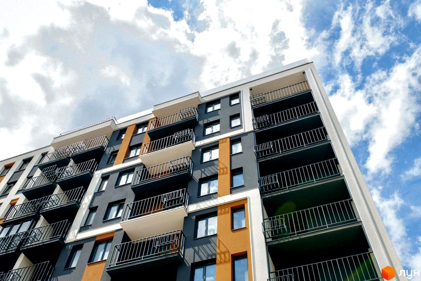 Багатоповерховий будинок Житлового комплексу КЕЛЬЦЕ з комбінованим фасадом у сірих, білих та помаранчевих тонах, обладнаний балконами з металевими огорожами.