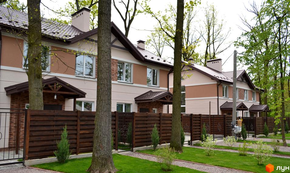 Котеджне містечко Sweet Home: двоповерхові будинки з бежево-коричневими фасадами та коричневими дахами. Доглянута територія з газонами та деревами.