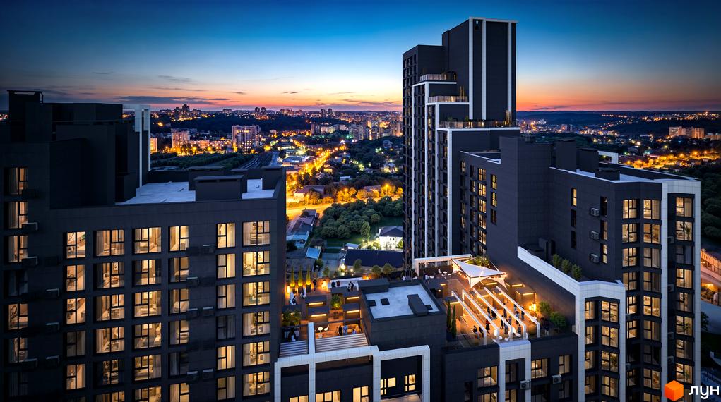 Житловий комплекс Nordica Residence ввечері. Високі темні будинки з освітленими вікнами та терасами на даху з людьми.