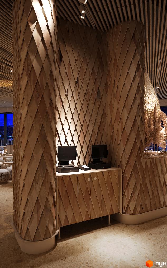 Інтер'єр Апарт-готель IKON Resort: стіни та колони оздоблені дерев'яними ромбовидними панелями. З вікна відкривається вид на гірський пейзаж.