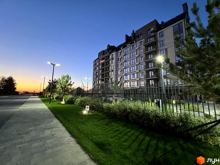 Житловий комплекс Park Residence з сірим фасадом та численними вікнами. Поруч доглянута прибудинкова територія з газоном та ліхтарями.