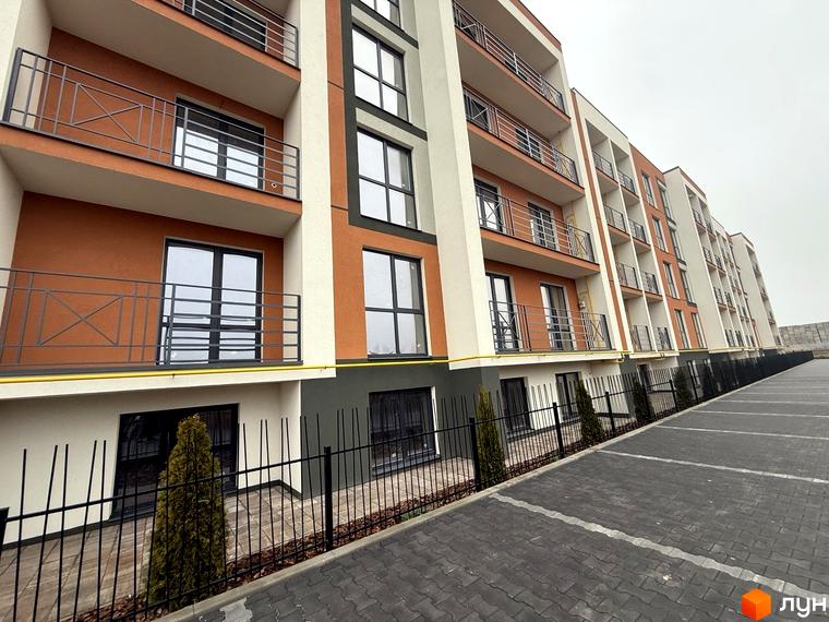 Житловий комплекс Brickwood 2 з оранжево-білими фасадами та балконами. Поруч розташований паркінг та зелені насадження.