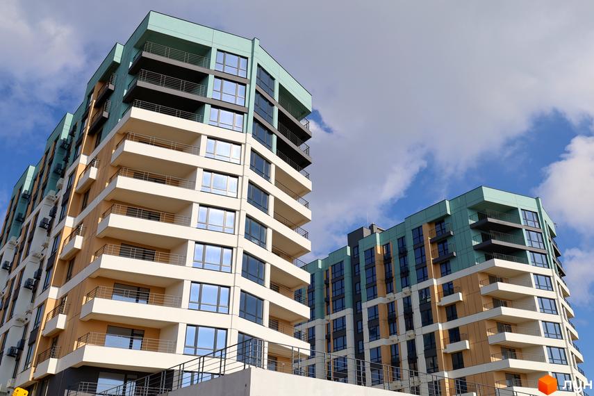 Житловий комплекс Парус. Багатоповерхові будинки з фасадами бірюзового, жовтого та білого кольорів, обладнані балконами та численними вікнами.