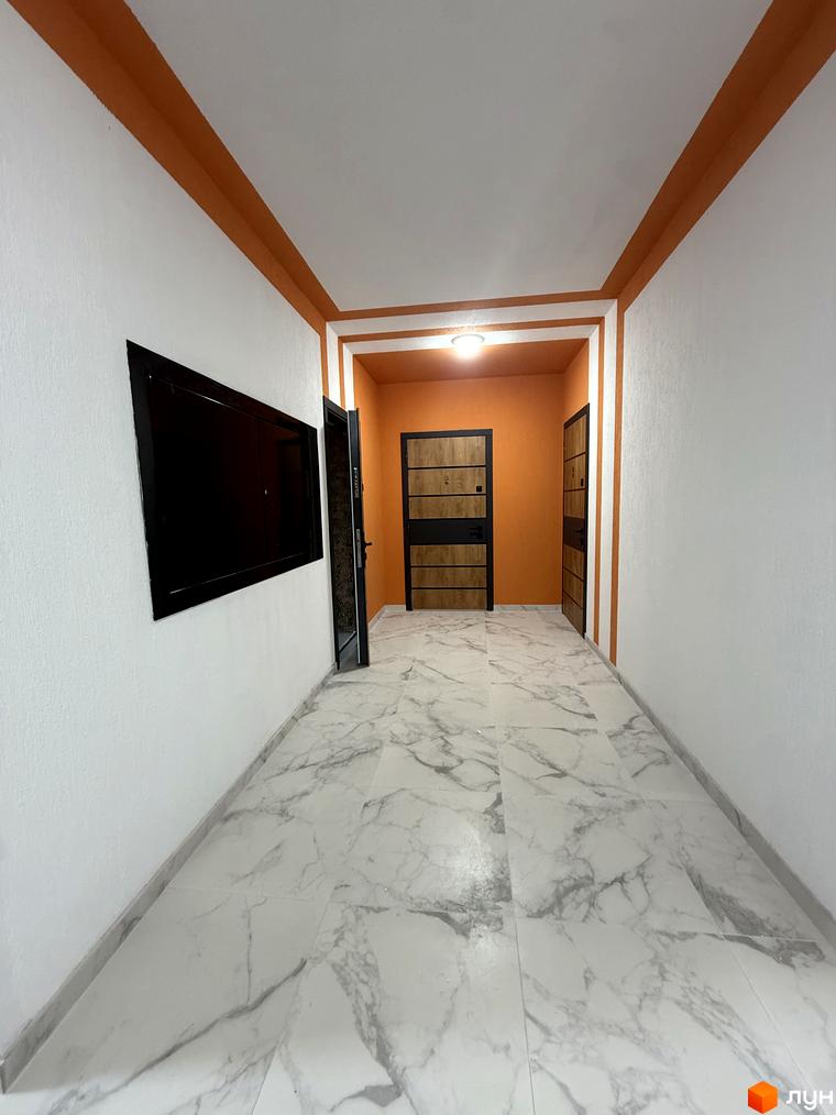 Комплекс Brickwood 2. Фото коридору з мармуровою плиткою на підлозі, білими стінами та помаранчевими елементами декору.