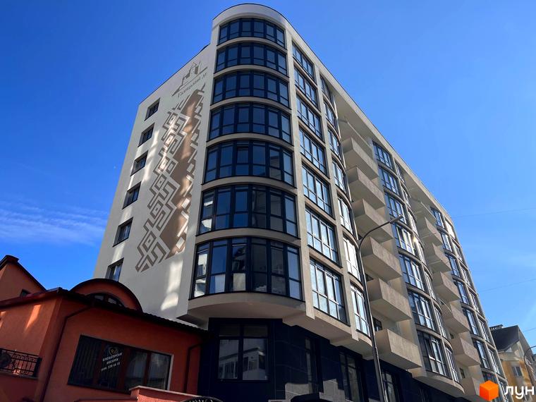 Галицький дім на вул. Володимира Великого, 16. Будинок з вигнутою секцією, темними вікнами, балконами та геометричним візерунком на фасаді.