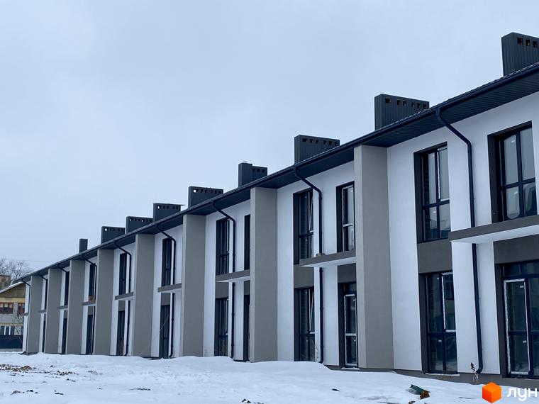 Ряд таунхаусів COMFORT TOWN з білими та сірими фасадами, темними вікнами та дахами. Прибудинкова територія вкрита снігом.