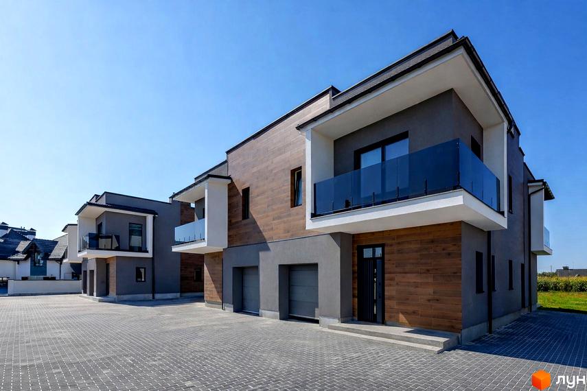 Ряд двоповерхових будинків Дуплекси на Похилій з темно-сірими фасадами, дерев'яними панелями та балконами зі скляними огорожами. Перед будинками вимощена бруківкою територія.