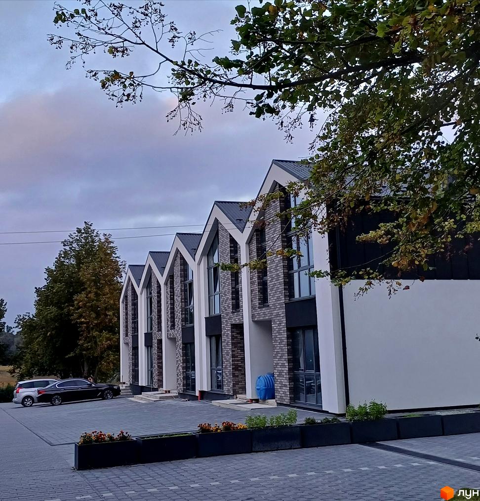 Котеджне містечко КМ Linden Park: фасади будинків з цегли та білої штукатурки, великі вікна, сірий дах. Прибудинкова територія з паркуванням та зеленими зонами.