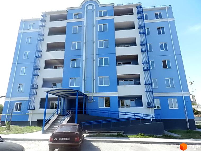 Новобудова Пролісок з синьо-білим фасадом та численними вікнами. Вхідна група з навісом та пандусом, прибудинкова територія з озелененням.