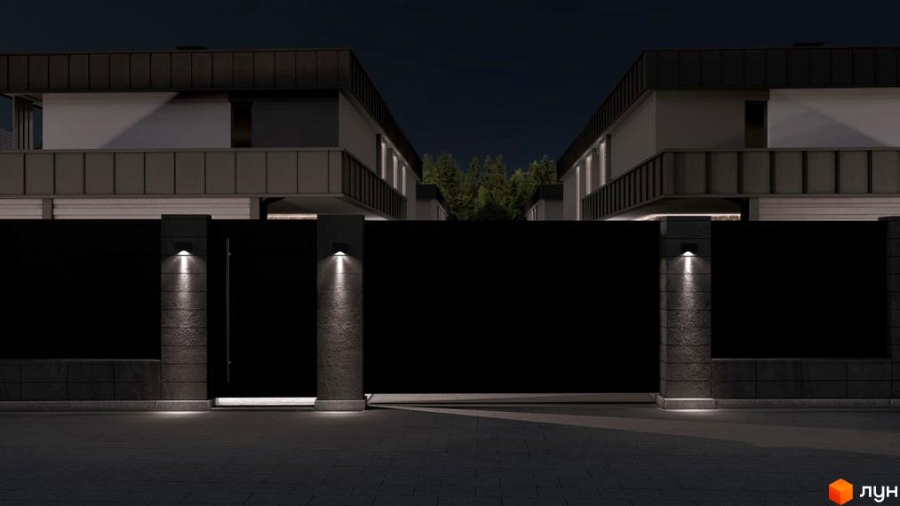 Нічна фасадна частина новобудови вул. Сонячна, 43, з підсвіченим парканом та сучасним освітленням. Територія перед будинком вимощена плиткою.