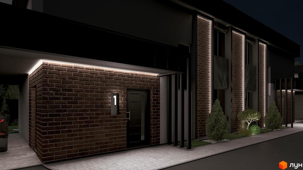 Фасад будинку з темно-цегляними стінами та підсвічуванням вночі. Перед будинком доріжка та зелені насадження з точковим освітленням.