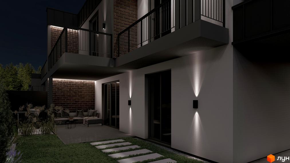 Багаторівневий будинок з цегляними вставками та зовнішнім освітленням на вул. Сонячна, 43. Навколо будинку газон та патіо.