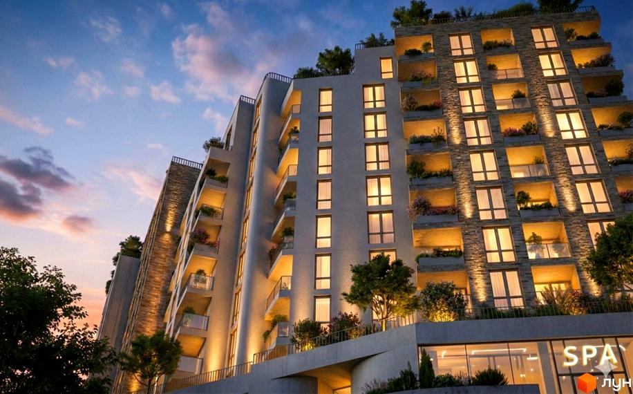 Житловий комплекс SHELEST Residence & SPA з освітленими вікнами, балконами та зеленими насадженнями на фасаді.