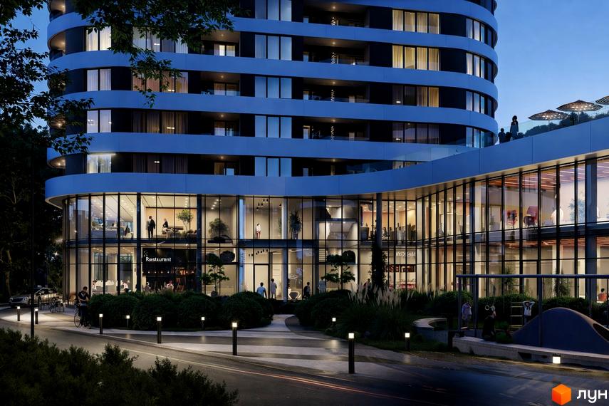 Багатоповерховий будинок Житлового комплексу Липські вежі з вигнутим фасадом та скляними вікнами. Прибудинкова територія має озеленення, доріжки та вечірнє освітлення.