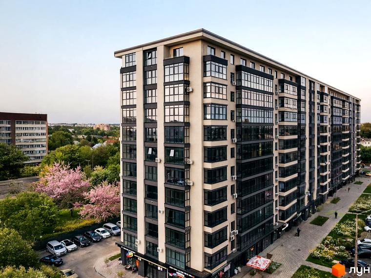 Житловий комплекс Династія має багатоповерховий будинок зі світлим фасадом та великими вікнами. Навколо будинку є зелені насадження, парковка та пішохідні зони.