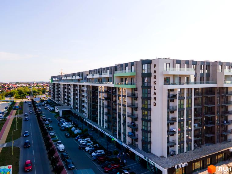Новобудова PARK LAND з багатоповерховими секціями та балконами, поруч дорога з автомобілями та житловими будинками.