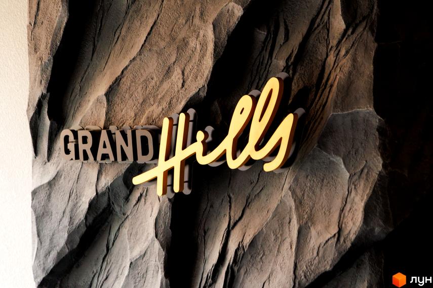 Фасадна вивіска Житлового комплексу Grand Hills на рельєфній стіні з об'ємними літерами.