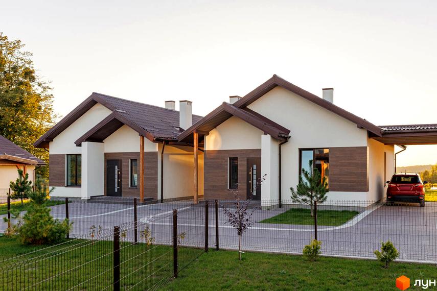 Котеджне містечко Буде Дім. Деревач: два одноповерхові будинки з коричневими дахами та біло-коричневими фасадами. Перед будинками доріжка, зелений газон з огорожею та червоний автомобіль.