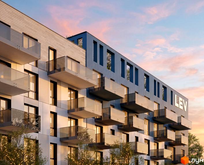 Зовнішній вигляд новобудови ЖК VERO з балконами та панорамними вікнами на тлі вечірнього неба. Навколо будівлі дерева з гірляндами.