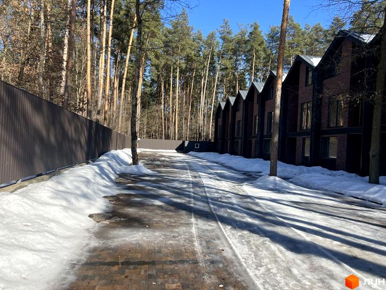 Таунхаус Forest Lane: фасади будинків з цегли та даху, що нагадує трикутник, на тлі лісу. Прибудинкова територія з доріжкою та залишками снігу.