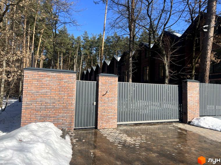 Таунхаус Forest Lane - цегляні колони та сітчастий паркан перед будинками. Прибудинкова територія з бруківки та снігу.