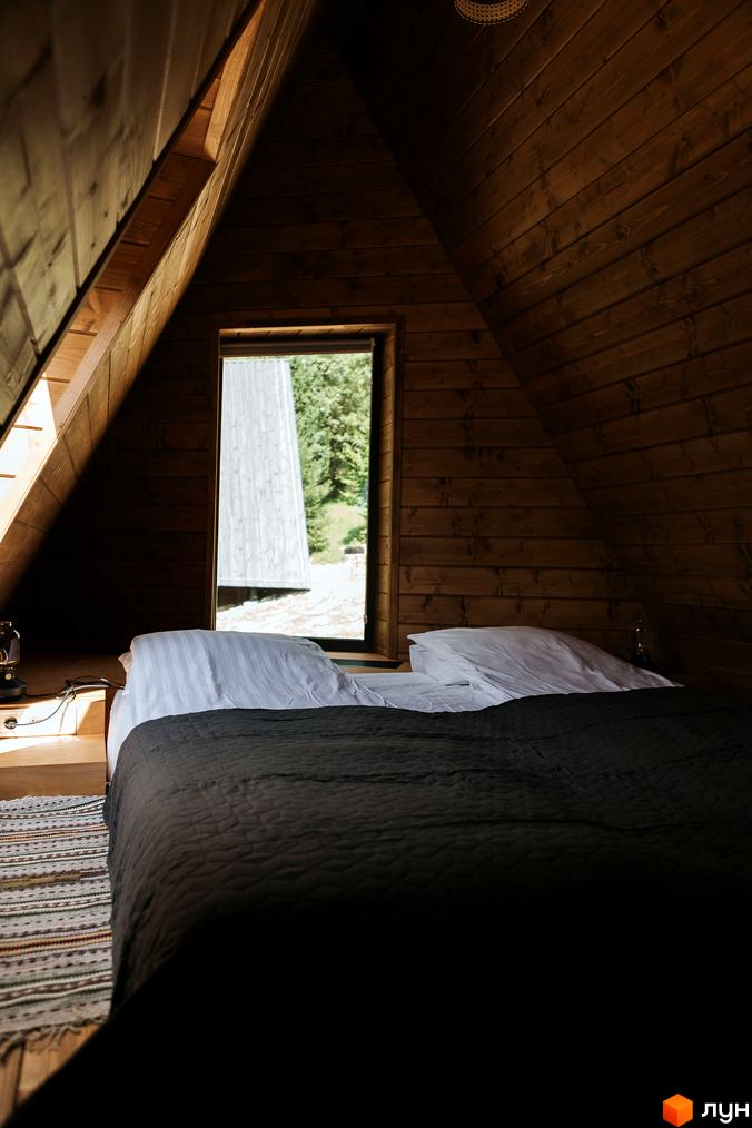 Комплекс відпочинку УЛІС Ворохта: спальня з дерев'яними стінами, вікном та видом на сусідній дерев'яний будинок серед зелені.
