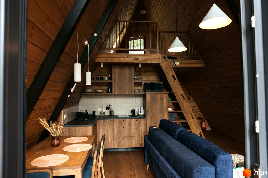 Інтер'єр дерев'яного будинку Комплексу відпочинку УЛІС Ворохта з обладнаною кухнею, обідньою зоною та сходами на мансарду.
