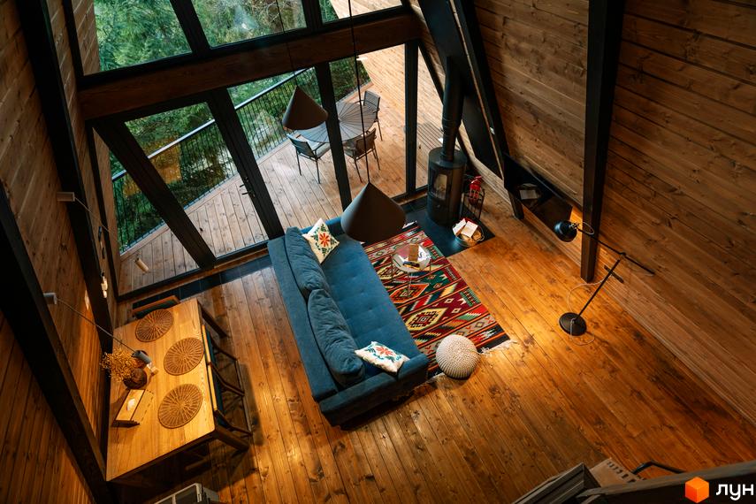Інтер'єр будинку Комплексу відпочинку УЛІС Ворохта: простора вітальня з дерев'яними стінами, великими вікнами та видом на ліс.