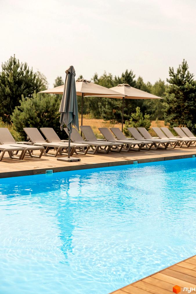 Зона відпочинку Комплексу відпочинку УЛІС Дудки з басейном, дерев'яною терасою та шезлонгами під парасольками.