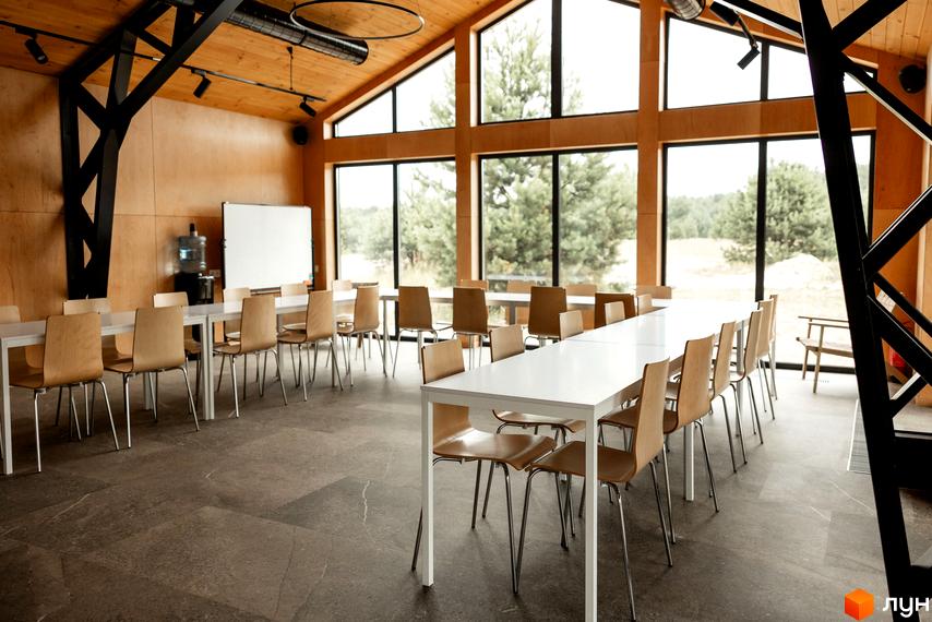 Інтер'єр затишної зали для заходів комплексу відпочинку УЛІС Дудки з дерев'яними стінами та великими вікнами, що виходять на ліс.