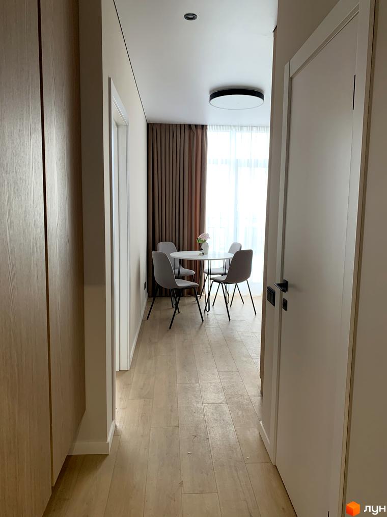 Інтер'єр квартири в Житловому комплексі Fine Flats: світлий коридор з дерев'яною підлогою, що веде до обідньої зони.